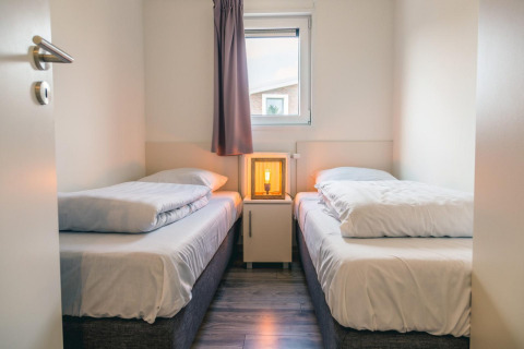 Chambre lumineuse avec deux lits simples, table de nuit et lampe à Hackfort 8, De Kraaijenbergse Plassen.