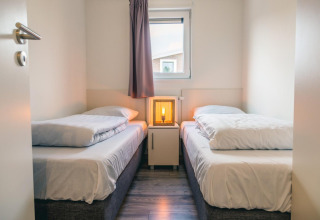 Heldere kamer met twee eenpersoonsbedden, nachtkastje en lamp bij Hackfort 8, De Kraaijenbergse Plassen.