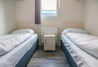 Habitación con dos camas individuales, ropa de cama blanca y una mesita de noche en Hackfort 8, De Kraaijenbergse Plassen.