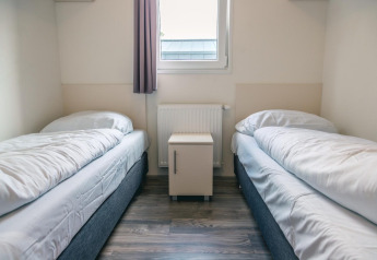 Zimmer mit zwei Einzelbetten, weißer Bettwäsche und Nachttisch im Hackfort 8 bei De Kraaijenbergse Plassen.
