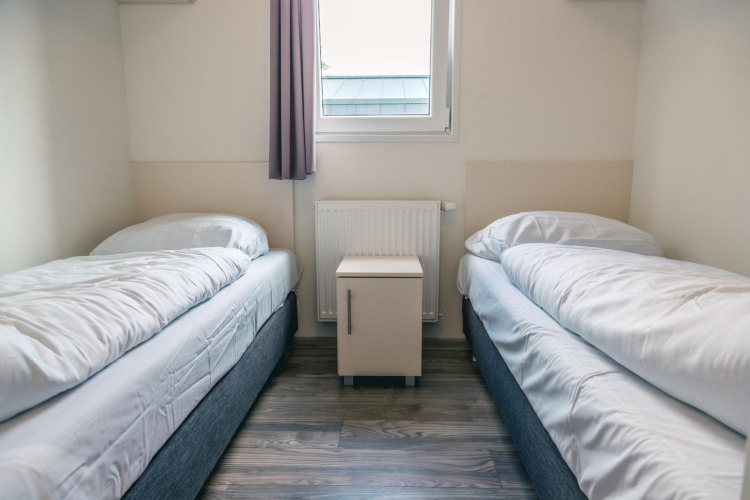 Habitación con dos camas individuales, ropa de cama blanca y una mesita de noche en Hackfort 8, De Kraaijenbergse Plassen.