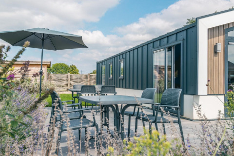 Terras met tuinset en parasol bij Hackfort 8 lodge, De Kraaijenbergse Plassen, Nederland.