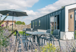Terras met tuinset en parasol bij Hackfort 8 lodge, De Kraaijenbergse Plassen, Nederland.