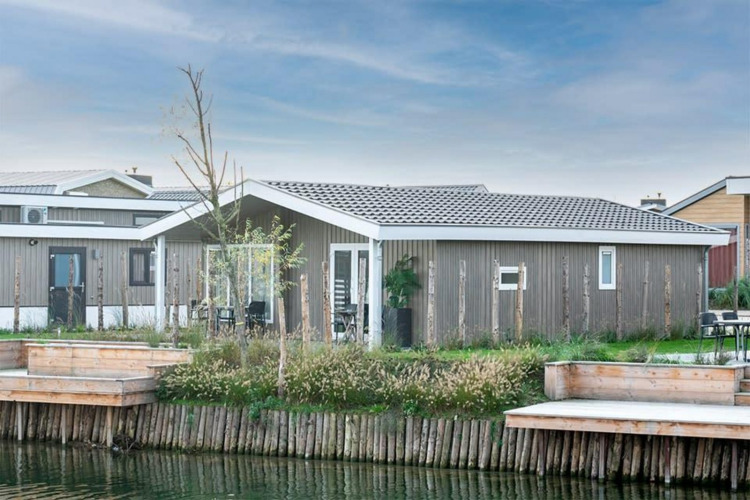 Modern waterfront lodge with wooden siding and terrace, situated at Hackfort Waterfront 4 on the water.