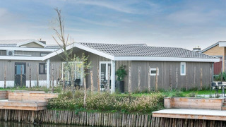 Lodge moderne en bois au bord de l'eau avec terrasse, situé à Hackfort Waterfront 4, vu depuis l'extérieur.