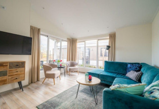 Soggiorno moderno del lodge Hackfort Waterfront 4 a De Kraaijenbergse Plassen nei Paesi Bassi, con ampie finestre.