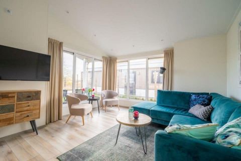 Soggiorno moderno del lodge Hackfort Waterfront 4 a De Kraaijenbergse Plassen nei Paesi Bassi, con ampie finestre.