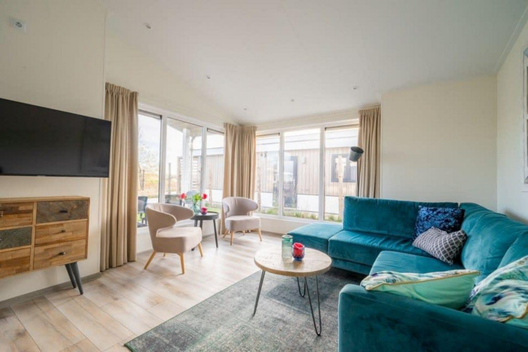 Modern living room at Hackfort Waterfront 4 lodge in De Kraaijenbergse Plassen, Netherlands, with large windows.