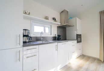 Moderne keuken met witte kasten, RVS-apparaten en een grijs aanrecht in Hackfort Waterfront 4 lodge.