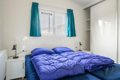 Dormitorio con dos camas individuales y ropa de cama azul en Hackfort Waterfront 4, De Kraaijenbergse Plassen, Países Bajos.