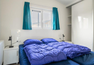 Schlafzimmer mit zwei Einzelbetten, blauer Bettwäsche und Fenster im Hackfort Waterfront 4, De Kraaijenbergse Plassen.
