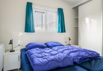 Chambre avec lits jumeaux, literie bleue et fenêtre au Hackfort Waterfront 4, De Kraaijenbergse Plassen, Pays-Bas.