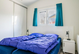 Dormitorio luminoso en Hackfort Waterfront 4 con ropa de cama azul en De Kraaijenbergse Plassen, Países Bajos.