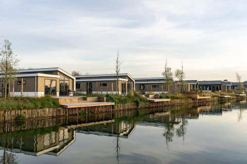 Moderne hytter ved vandkanten på Hackfort Waterfront 6, omgivet af fredelige omgivelser og natur.