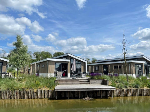 Modernas cabañas Hackfort Waterfront 6 en De Kraaijenbergse Plassen, Países Bajos, junto al agua y cielo azul.