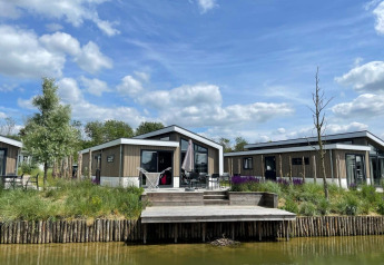 Modernas cabañas Hackfort Waterfront 6 en De Kraaijenbergse Plassen, Países Bajos, junto al agua y cielo azul.