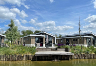 Moderne Hackfort Waterfront 6-lodges ved De Kraaijenbergse Plassen, Holland, under blå himmel med skyer.