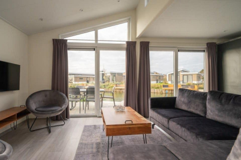 Sala moderna en Hackfort Waterfront 6, De Kraaijenbergse Plassen, Países Bajos, con vista al agua.