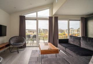 Sala moderna en Hackfort Waterfront 6, De Kraaijenbergse Plassen, Países Bajos, con vista al agua.