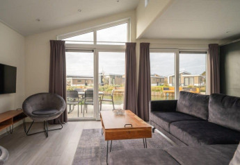 Sala moderna en Hackfort Waterfront 6, De Kraaijenbergse Plassen, Países Bajos, con vista al agua.