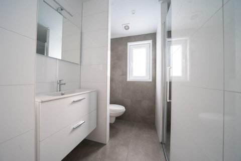 Salle de bain moderne avec mobilier blanc, lavabo, miroir, toilettes et fenêtre à Hackfort Waterfront 6, Pays-Bas.