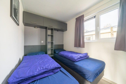 Deux lits simples avec draps bleus au Hackfort Waterfront 6 aux Kraaijenbergse Plassen, Pays-Bas.