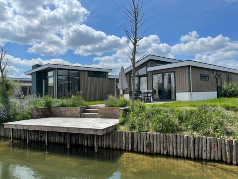 Lodge moderne Hackfort Waterfront 6 aux De Kraaijenbergse Plassen, Pays-Bas, avec terrasse sur l’eau.