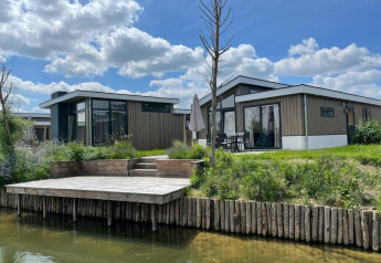 Lodge moderne Hackfort Waterfront 6 aux De Kraaijenbergse Plassen, Pays-Bas, avec terrasse sur l’eau.