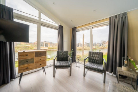 Interior moderno de la cabaña Hackfort Waterfront 8 en De Kraaijenbergse Plassen, Países Bajos, con amplias ventanas.
