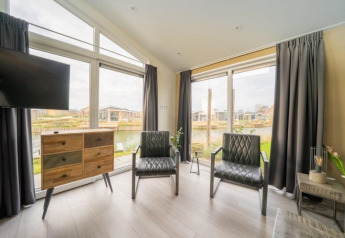 Moderne leefruimte van Hackfort Waterfront 8 lodge aan De Kraaijenbergse Plassen in Nederland, met grote ramen.