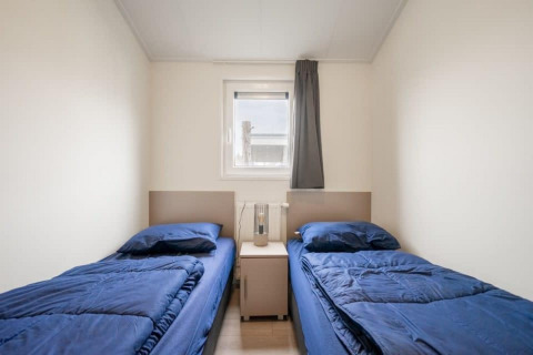 Zwei Einzelbetten mit blauer Bettwäsche in einem Zimmer im Hackfort Waterfront 8, De Kraaijenbergse Plassen, Niederlande.