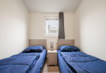 Twee eenpersoonsbedden met blauwe lakens in een kamer van Hackfort Waterfront 8, De Kraaijenbergse Plassen, Nederland.