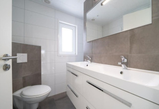 Modernes Badezimmer mit Doppelwaschbecken, großem Spiegel und WC im Hackfort Waterfront 8 in den Niederlanden.