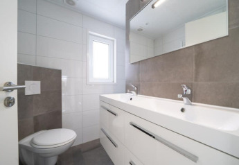 Moderne badkamer met dubbele lavabo, grote spiegel en toilet in Hackfort Waterfront 8, De Kraaijenbergse Plassen.