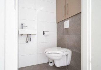 Moderne, compacte badkamer met zwevend toilet en kleine lavabo op Hackfort Waterfront 8 in Nederland.