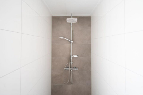 Moderne douche met wit en beige tegelwanden in Hackfort Waterfront 8, De Kraaijenbergse Plassen, Nederland.