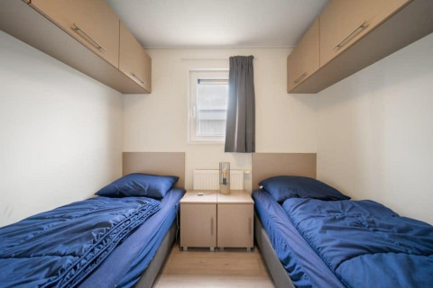 Zwei Einzelbetten mit blauer Bettwäsche in einem einfachen Zimmer bei Hackfort Waterfront 8, Niederlande.