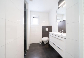 Baño moderno en Pavilion 6, De Kraaijenbergse Plassen, Países Bajos, con azulejos blancos y sanitarios elegantes.