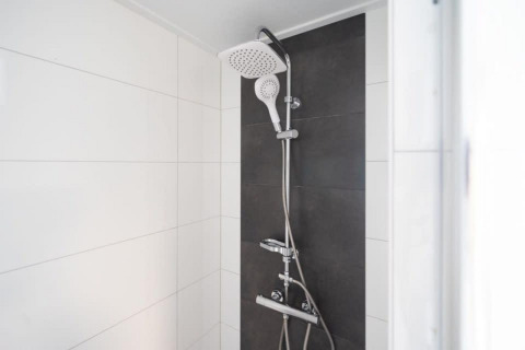 Modern shower with dual showerheads and white and dark tiles, Pavilion 6, De Kraaijenbergse Plassen, Netherlands.