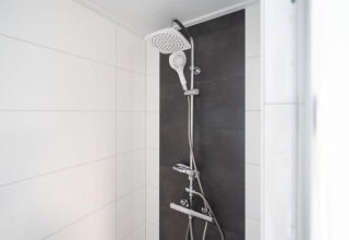 Modern shower with dual showerheads and white and dark tiles, Pavilion 6, De Kraaijenbergse Plassen, Netherlands.