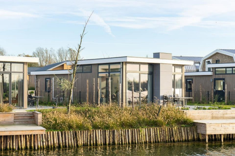 Moderne pavilionlodge aan het water met grote ramen en terras, Pavilion Waterfront 6, omgeven door natuur.