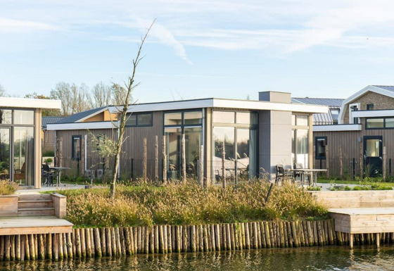 Moderne pavilionlodge aan het water met grote ramen en terras, Pavilion Waterfront 6, omgeven door natuur.