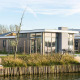 Moderne pavillonlodge ved vandet med store vinduer og terrasse, Pavilion Waterfront 6, omgivet af natur.