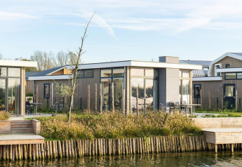 Modern pavilion lodge by the water with large windows and patio, Pavilion Waterfront 6, surrounded by nature.