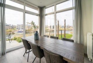 Spisestue i Pavilion Waterfront 6-lodge på De Kraaijenbergse Plassen, udsigt til vand og hytter.