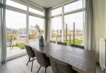 Spisestue i Pavilion Waterfront 6-lodge på De Kraaijenbergse Plassen, udsigt til vand og hytter.