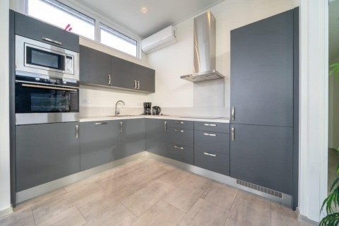 Moderne keuken met grijze kasten en witte werkbladen in Pavilion Waterfront 6, Kraaijenbergse Plassen.