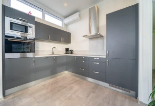 Moderne keuken met grijze kasten en witte werkbladen in Pavilion Waterfront 6, Kraaijenbergse Plassen.