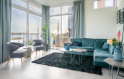 Moderne stue med store vinduer, blå sofa og udsigt til vandet ved Pavilion Waterfront 8, Nederlandene.