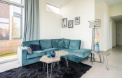 Moderne stue i Pavilion Waterfront 8, De Kraaijenbergse Plassen, Holland, med blå sofa og glasvinduer.